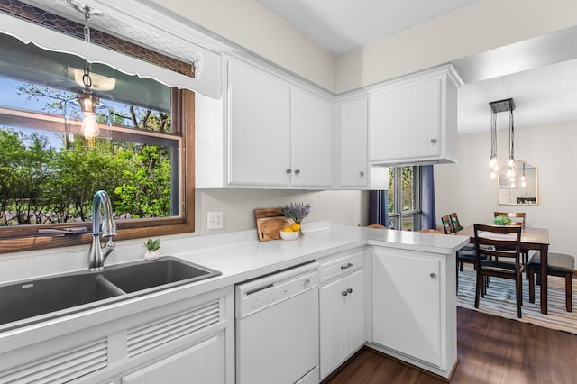 kitchen featuring white dishwasher, a sink, light countertops, and white cabinets