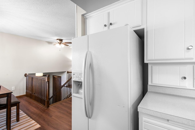 kitchen featuring white refrigerator with ice dispenser, dark wood finished floors, ceiling fan, white cabinets, and a textured ceiling
