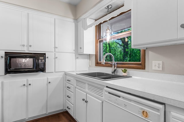 kitchen featuring a sink, black microwave, white dishwasher, light countertops, and white cabinetry