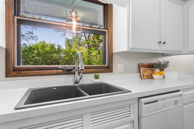 kitchen with white dishwasher, light countertops, a sink, and white cabinets