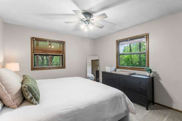 bedroom featuring light carpet, baseboards, and a ceiling fan