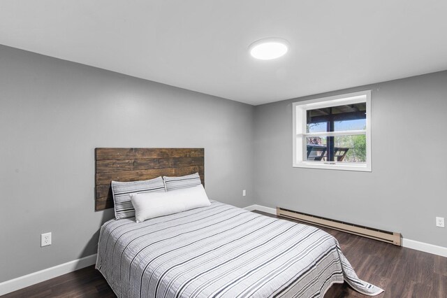 bedroom featuring baseboard heating, baseboards, and wood finished floors