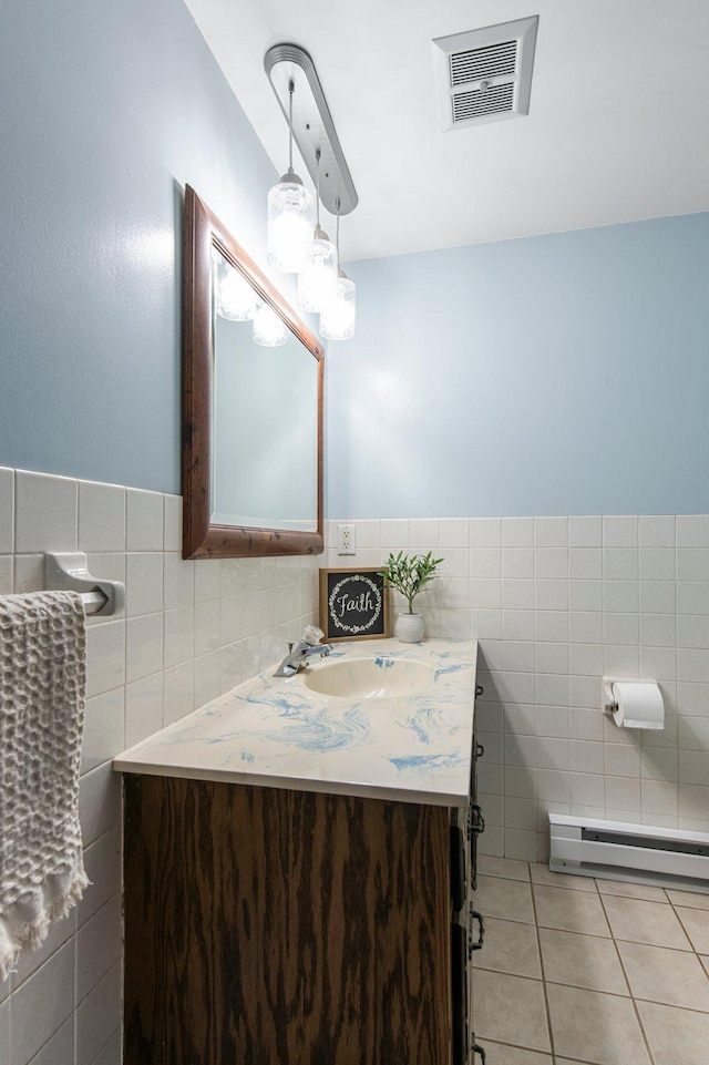 half bath featuring tile walls, a baseboard radiator, tile patterned floors, vanity, and a wainscoted wall