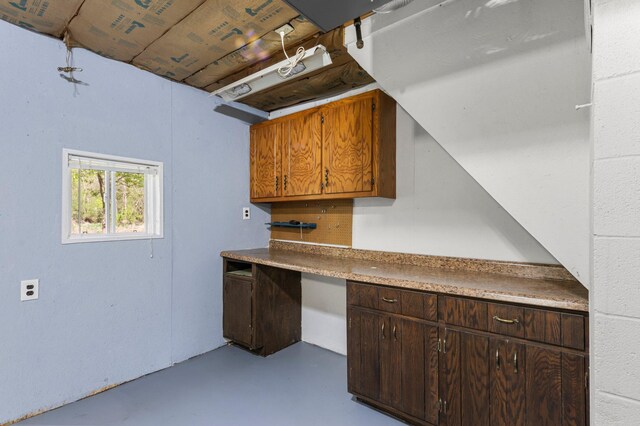 kitchen featuring finished concrete flooring, a desk, and dark brown cabinetry