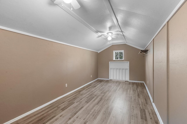 additional living space with a ceiling fan, vaulted ceiling, a textured ceiling, wood finished floors, and baseboards