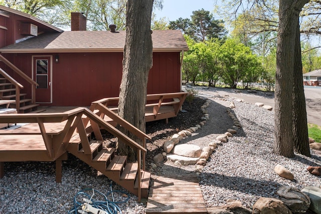 view of side of property featuring stairway, a chimney, a shingled roof, and a wooden deck