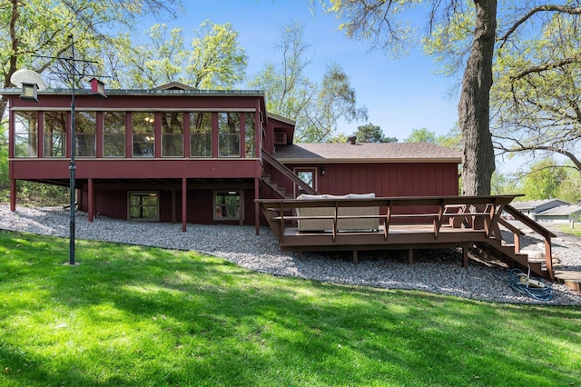 rear view of property featuring a sunroom, stairs, a deck, a lawn, and a shingled roof