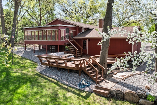 rear view of property featuring stairs, a sunroom, a wooden deck, a chimney, and a shingled roof