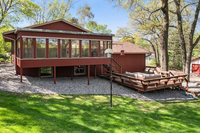 rear view of property featuring a sunroom, a deck, and a lawn