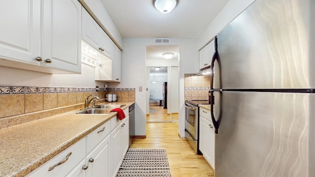 450 Ford Rd Unit 217, Saint Louis Park, MN 55426 - kitchen featuring appliances with stainless steel finishes, decorative backsplash, under cabinet range hood, light wood finished floors, and light countertops