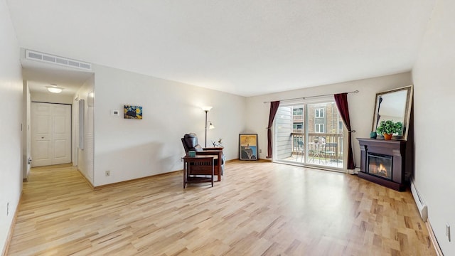450 Ford Rd Unit 217, Saint Louis Park, MN 55426 - sitting room featuring light wood-type flooring, a glass covered fireplace, and a baseboard radiator