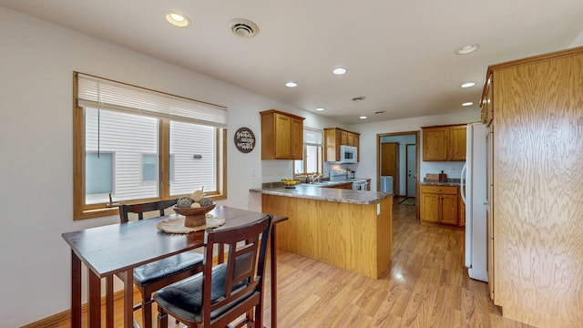 930 5th Ave, Goodhue, MN 55027 - kitchen with white appliances, a peninsula, visible vents, a sink, and light wood finished floors