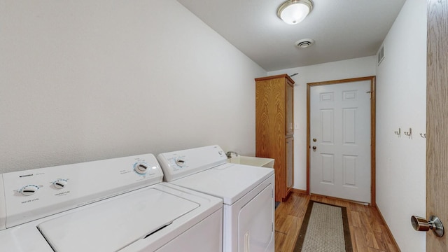 930 5th Ave, Goodhue, MN 55027 - laundry area featuring washer and dryer, cabinet space, visible vents, and light wood-style flooring