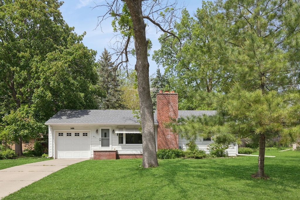 611 7th St E, Northfield, MN 55057 - view of front of property with a chimney, a garage, a front lawn, concrete driveway, and roof with shingles