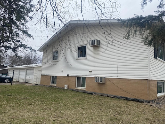 back of property with a garage, an AC wall unit, and a lawn