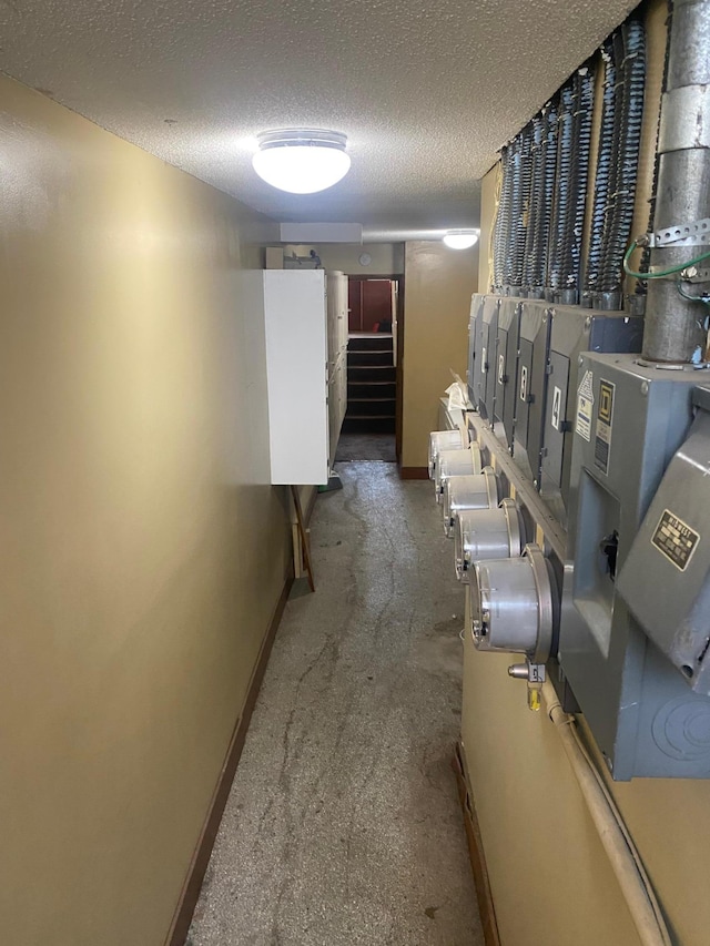 hallway featuring a textured ceiling, baseboards, and stairway
