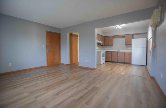 unfurnished living room with light wood-style floors, a sink, and baseboards