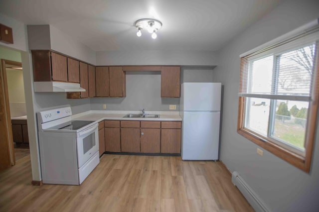 kitchen featuring white appliances, light countertops, under cabinet range hood, light wood-style floors, and a sink