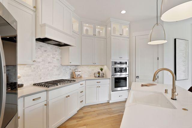 4036 Arbor Dr, Woodbury, MN 55129 - kitchen featuring appliances with stainless steel finishes, a sink, decorative light fixtures, light countertops, and white cabinetry