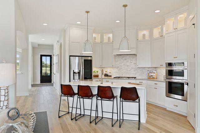 4036 Arbor Dr, Woodbury, MN 55129 - kitchen with appliances with stainless steel finishes, light countertops, light wood-type flooring, a center island with sink, and recessed lighting