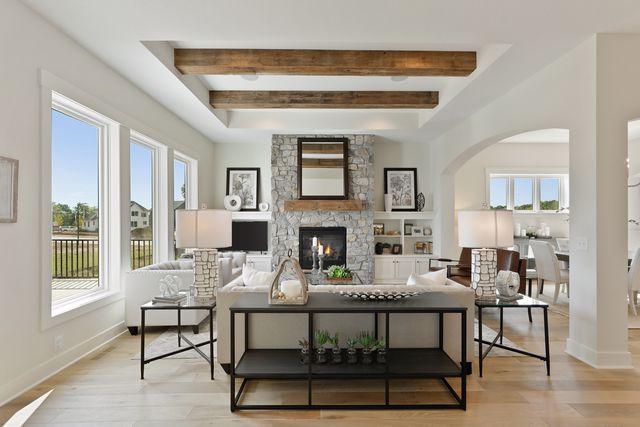4036 Arbor Dr, Woodbury, MN 55129 - living area with arched walkways, beam ceiling, a fireplace, baseboards, and light wood-style flooring