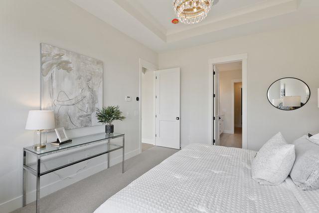 4036 Arbor Dr, Woodbury, MN 55129 - carpeted bedroom with a chandelier, baseboards, and a tray ceiling