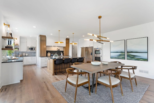 dining space featuring recessed lighting, a notable chandelier, light wood-type flooring, and visible vents