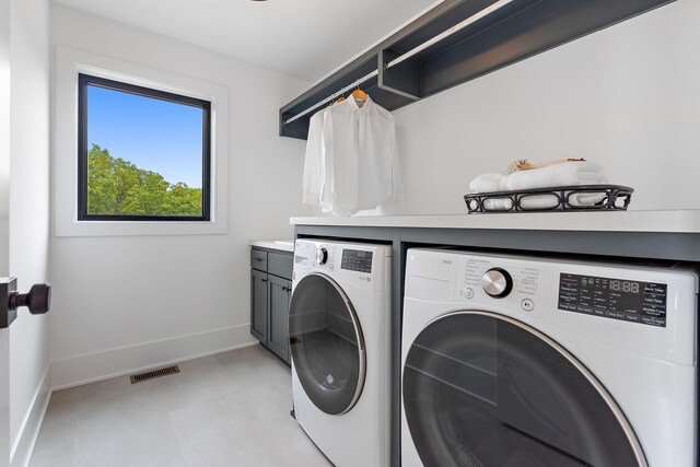 clothes washing area with visible vents, cabinet space, baseboards, light floors, and washer and clothes dryer