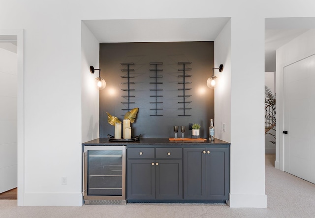 bar featuring indoor wet bar, baseboards, wine cooler, and light carpet