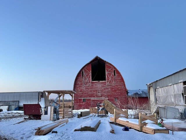 view of snow covered exterior featuring a barn, an outdoor structure, and a gambrel roof