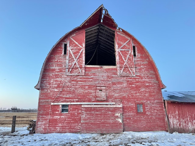 snow covered property featuring an outdoor structure, a gambrel roof, and a barn