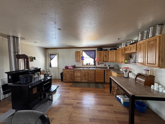 kitchen featuring a textured ceiling, open shelves, a sink, dark countertops, and light wood-type flooring
