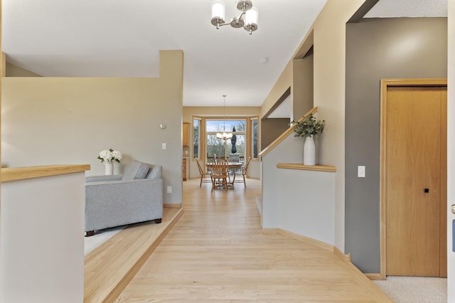 corridor with baseboards, a notable chandelier, and wood finished floors