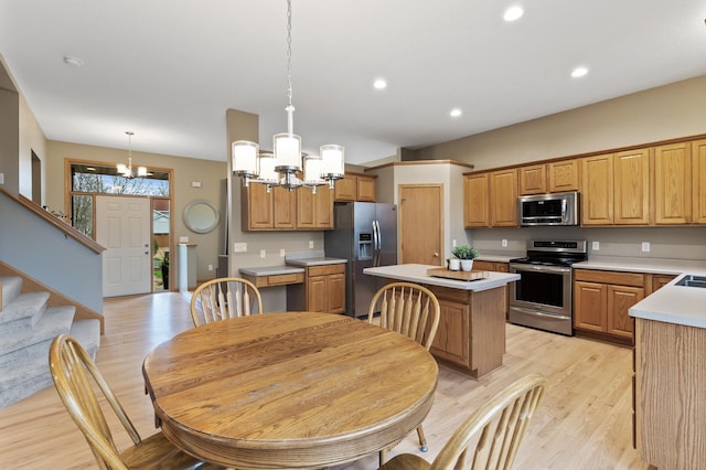 kitchen with an inviting chandelier, a kitchen island, stainless steel appliances, and light wood-type flooring