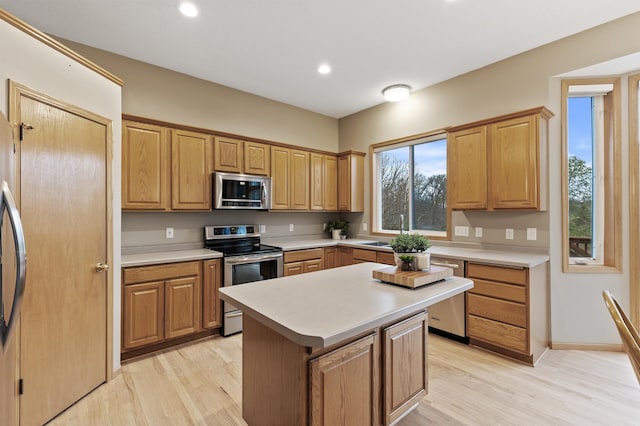 kitchen with light countertops, appliances with stainless steel finishes, light wood-style floors, and a kitchen island