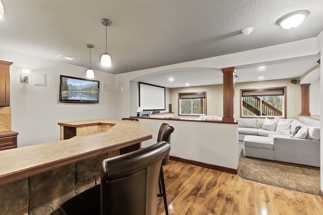 bar with arched walkways, decorative light fixtures, wood finished floors, ornate columns, and visible vents
