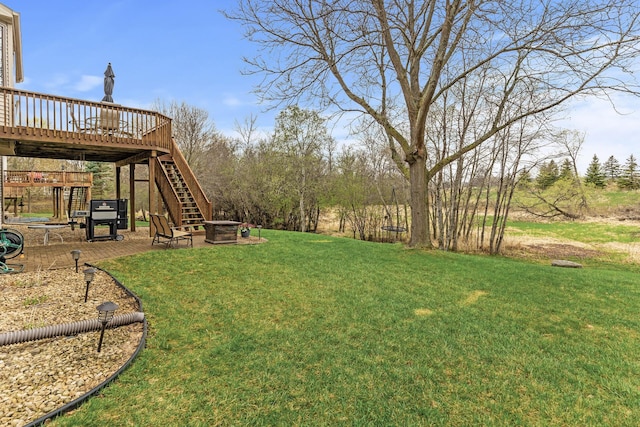 view of yard with a wooden deck, a fire pit, and stairway
