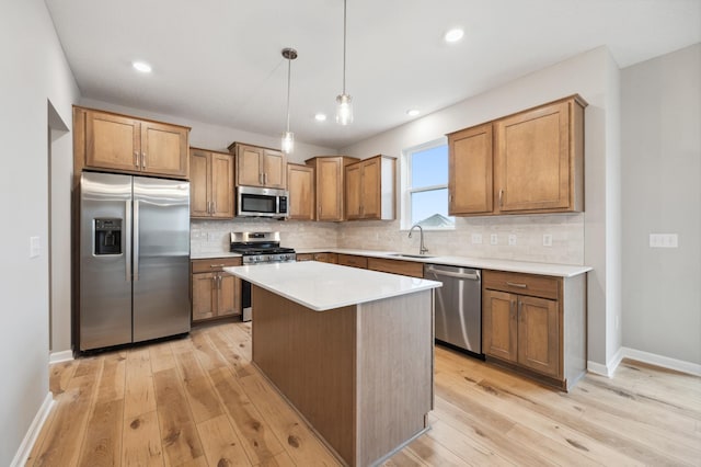 kitchen featuring light wood-style floors, appliances with stainless steel finishes, a sink, and backsplash