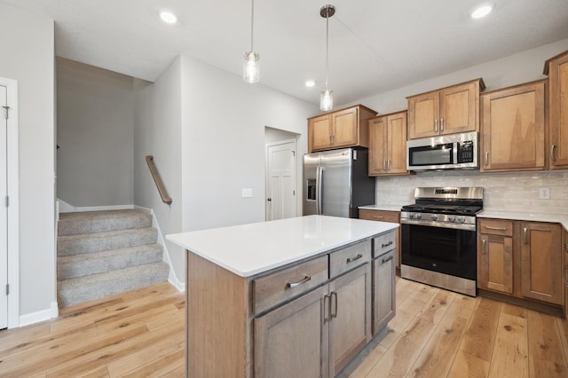 kitchen featuring light wood-style flooring, pendant lighting, decorative backsplash, and stainless steel appliances