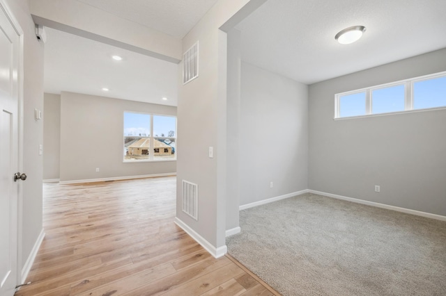 unfurnished room featuring recessed lighting, light wood-type flooring, visible vents, and baseboards