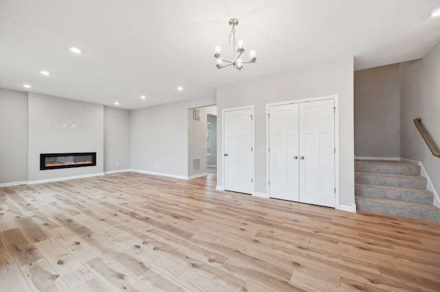 unfurnished living room with baseboards, light wood-type flooring, an inviting chandelier, recessed lighting, and stairs