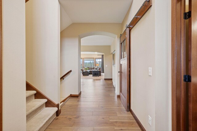 21804 Majestic Dr, Saint Augusta, MN 55320 - corridor with light wood-type flooring, arched walkways, and a barn door