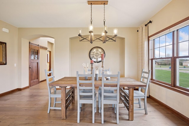 21804 Majestic Dr, Saint Augusta, MN 55320 - dining room featuring arched walkways, a barn door, baseboards, a chandelier, and light wood-style floors