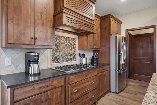 21804 Majestic Dr, Saint Augusta, MN 55320 - kitchen with custom exhaust hood, dark stone countertops, light wood-style flooring, backsplash, and stainless steel appliances