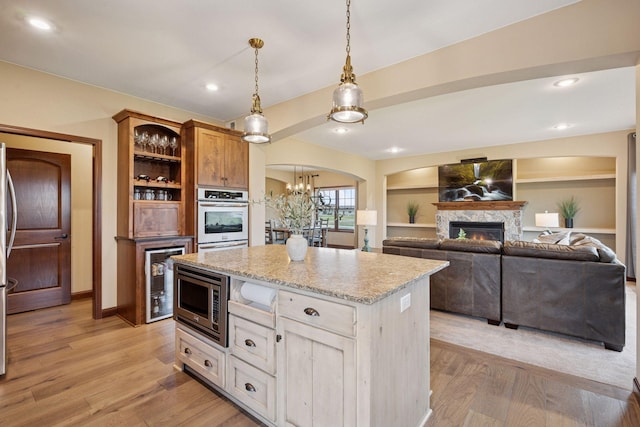 21804 Majestic Dr, Saint Augusta, MN 55320 - kitchen featuring light stone countertops, a fireplace, a center island, decorative light fixtures, and stainless steel appliances