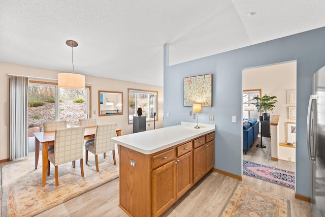 6108 Creek Line Dr, Minnetonka, MN 55345 - kitchen with decorative light fixtures, light countertops, brown cabinets, light wood finished floors, and a peninsula
