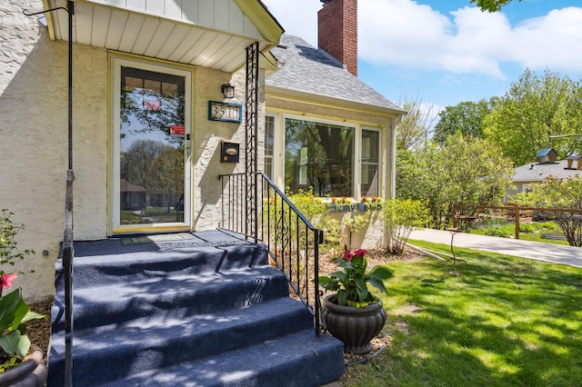 3511 Mckinley St NE, Minneapolis, MN 55418 - doorway to property featuring roof with shingles, a chimney, a lawn, and board and batten siding