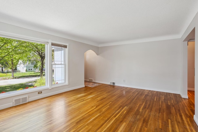 3511 Mckinley St NE, Minneapolis, MN 55418 - unfurnished room featuring arched walkways, wood finished floors, and baseboards