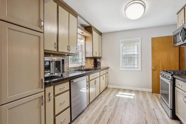 3511 Mckinley St NE, Minneapolis, MN 55418 - kitchen featuring stainless steel appliances, a sink, backsplash, dark countertops, and light wood finished floors