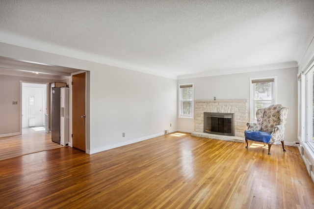 3511 Mckinley St NE, Minneapolis, MN 55418 - unfurnished living room featuring light wood-style floors, a fireplace, a textured ceiling, and baseboards